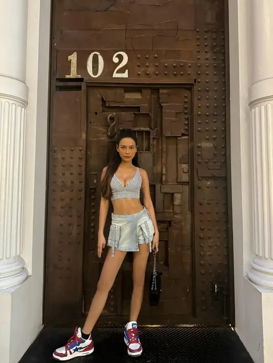 Tak melulu pakai celana jeans, Erika Carlina kenakan sneakers dengan paduan rok mini jeans. Bikin kakinya terlihat jenjang dengan striped croptop [@eri.carl]