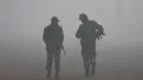Pasukan keamanan India berjalan di tengah polusi asap tebal yang menyelimuti kota New Delhi, India, Rabu (3/1). Kualitas udara yang semakin buruk dan kabut beracun menyelimuti seluruh kota. (Money SHARMA / AFP)