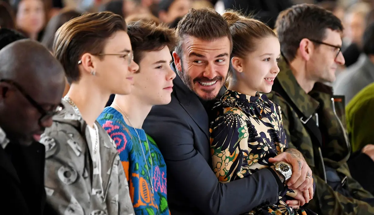Legenda Timnas Inggris, David Beckham, bersama anak-anaknya saat menyaksikan peragaan busana koleksi Victoria Beckham pada acara London Fashion Week (16/2/2020). (Photo by DANIEL LEAL-OLIVAS / AFP)