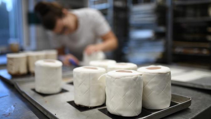 Andrea Schulz menyiapkan kue berbentuk tisu toilet di toko roti Schuerener Backparadies di Dortmund, Jerman, 26 Maret 2020. Kelangkaan kertas tisu toilet memunculkan ide bagi pemilik toko roti itu, Tim Kortuem, membuat kue menyerupai barang yang diburu warga di tengah Covid-19. (Ina FASSBENDER/AFP)