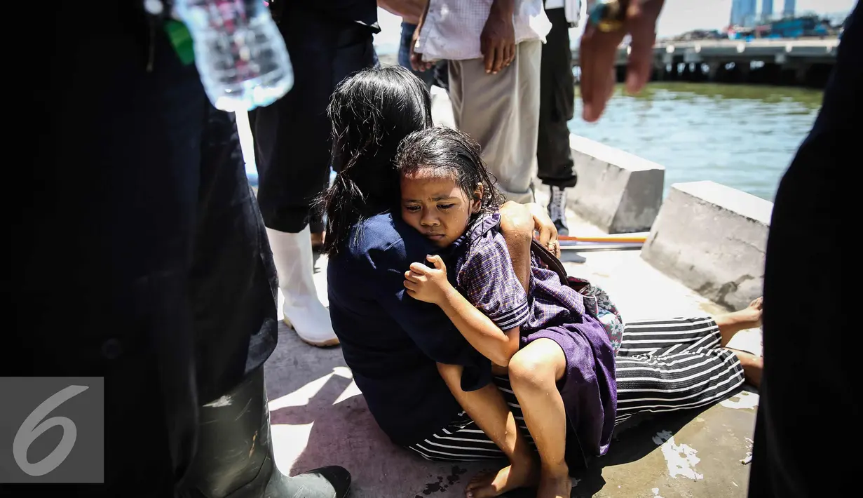 Seorang anak kecil yang terjatuh ke laut dipeluk ibunya di dermaga Muara Angke, Jakarta, Kamis (24/3). Akibat kelalaian ibunya seorang anak tercebur ke laut dan langsung di selamatkan warga dan prajurit TNI AL. (Liputan6.com/Faizal Fanani)