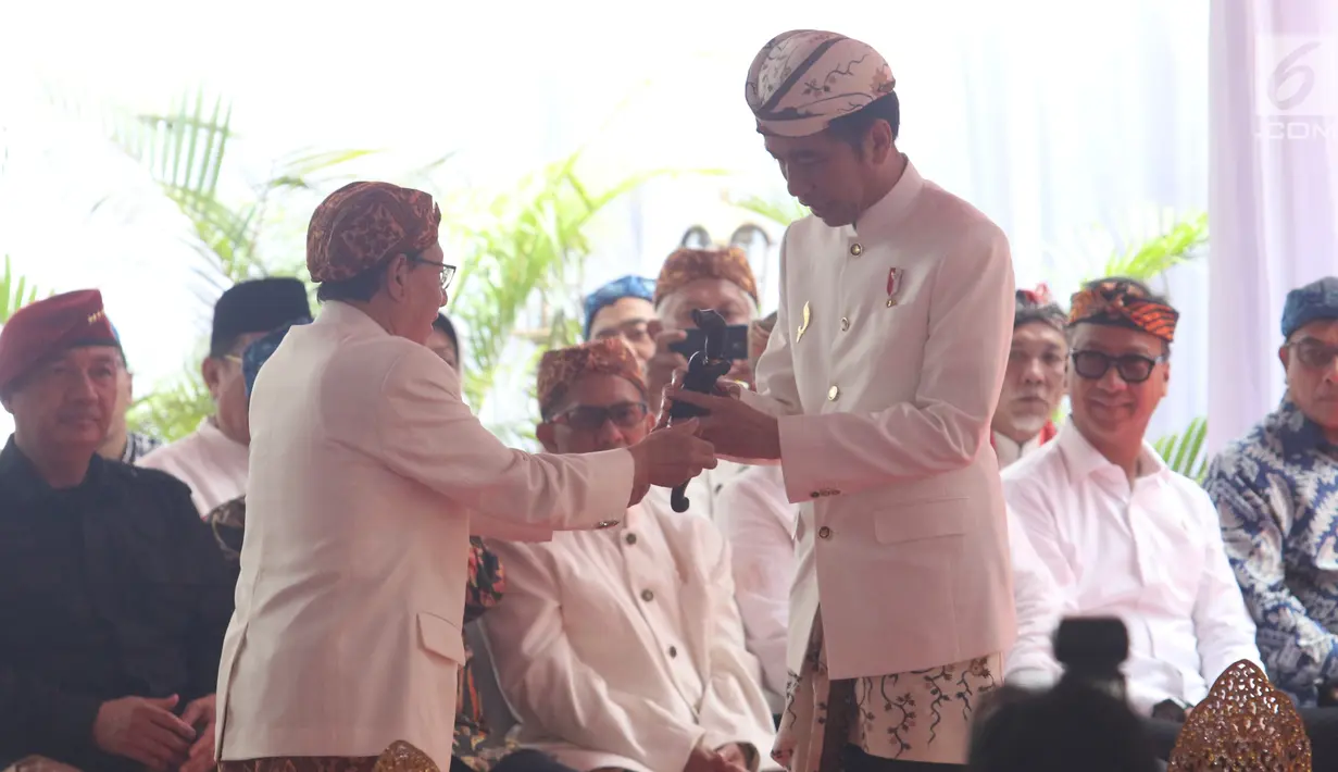 Presiden Joko Widodo (Jokowi) menerima kujang, senjata khas Sunda dalam prosesi penganugerahan gelar Pinisepuh dari Paguyuban Pasundan di Bandung, Minggu (11/11). Paguyuban Pasundan adalah ormas Sunda yang berdiri sejak 1913. (Liputan6.com/Angga Yuniar)