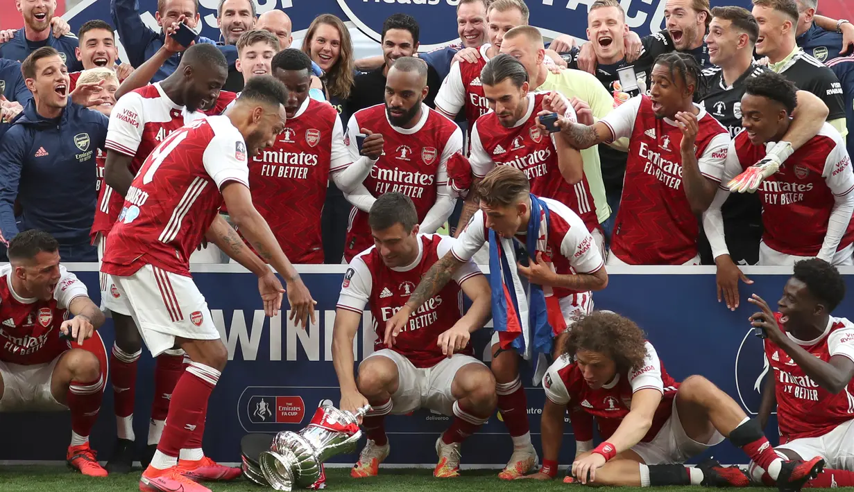 Striker Arsenal, Pierre-Emerick Aubameyang menjatuhkan trofi saat perayaan gelar juara Piala FA usai mengalahkan Chelsea pada pertandingan final Piala FA di stadion Wembley, Minggu (2/8/2020).  Aubameyang terlihat kaget sambil memegang kepalanya saat trofi terjatuh. (Catherine Ivill/Pool via AP)