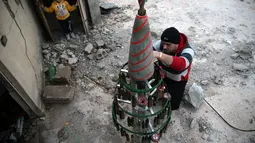 Sisa-sisa amunisi bekas perang di Suriah dimanfaatkan Akram untuk membuat sebuah pohon natal di Douma, Suriah, Jumat (23/12). (REUTERS/Bassam Khabieh)