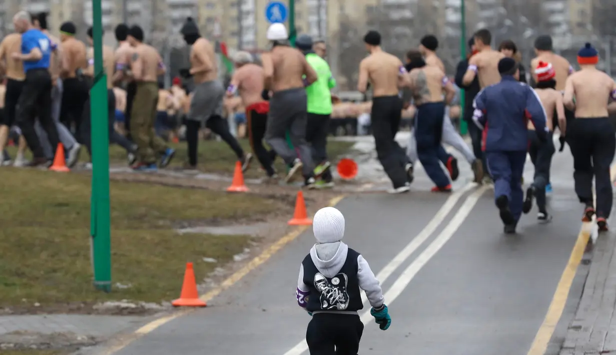 Seorang anak ikut berlari dalam acara "Real men's race" di Minsk, Belarusia, Kamis (23/2). Ratusan pria bertelanjang dada sambil berlari keliling Kota Minsk untuk memperingati Hari Pertahanan Tanah Air. (AP Photo/Sergei Grits)
