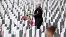 Pensiunan Angkatan Laut Amerika Serikat Yeoman Mark Stallins berjalan melewati deretan batu nisan saat akan memainkan Taps untuk keluarga prajurit yang gugur di sebuah kuburan di Pemakaman Nasional Fort Logan, Sheridan, Colorado, Amerika Serikat, 30 Mei 2022. (AP Photo/David Zalubowski)