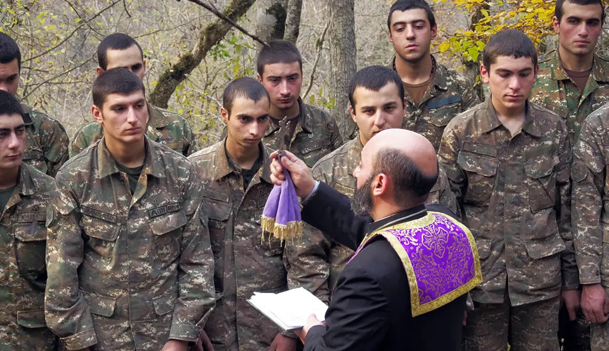 Pendeta Aristakes Hovhannisyan membaptis tentara etnis Armenia di sebuah kamp militer dekat garis depan konflik di wilayah separatis Nagorno-Karabakh, Azerbaijan, Senin (2/11/2020). Pasukan Armenia dan Azerbaijan saling menyalahkan atas serangan baru selama perebutan Nagorno-Karabakh. (AP Photo)