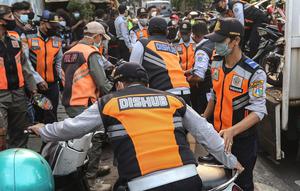 Petugas gabungan yang terdiri dari Satpol PP dan Dinas Perhubungan (Dishub) DKI Jakarta mengangkut motor yang terjaring razia ke atas truk di lokasi Citayam Fashion Week, kawasan Stasiun Dukuh Atas, Sudirman, Selasa (26/7/2022). Dishub DKI Jakarta mengamankan sebanyak 16 sepeda motor yang terpakir secara liar. (Liputan6.com/Faizal Fanani)