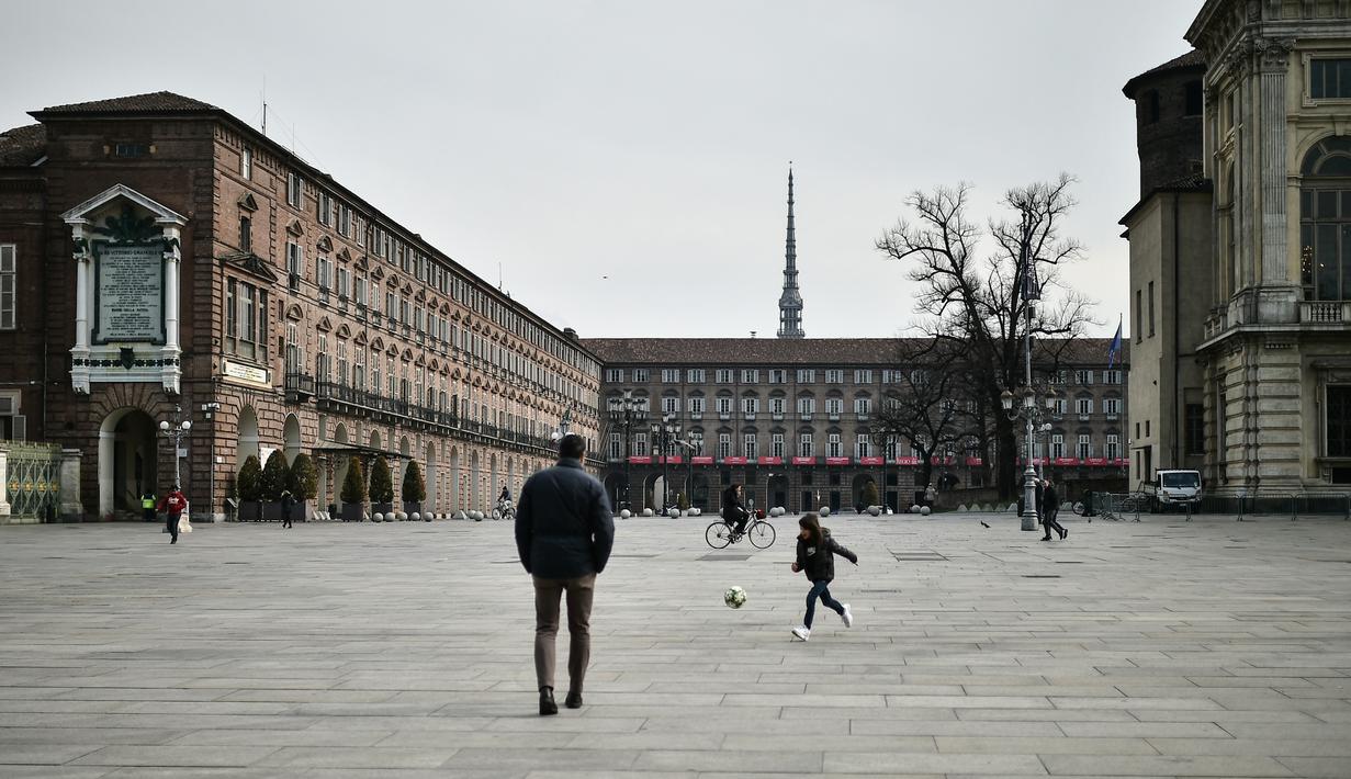 Seorang anak bermain bola di Piazza Castello, Turin, Italia, Senin (9/3/2020). Virus corona (COVID-19) di Italia telah mengakibatkan 463 orang meninggal dunia. (Marco BERTORELLO/AFP)
