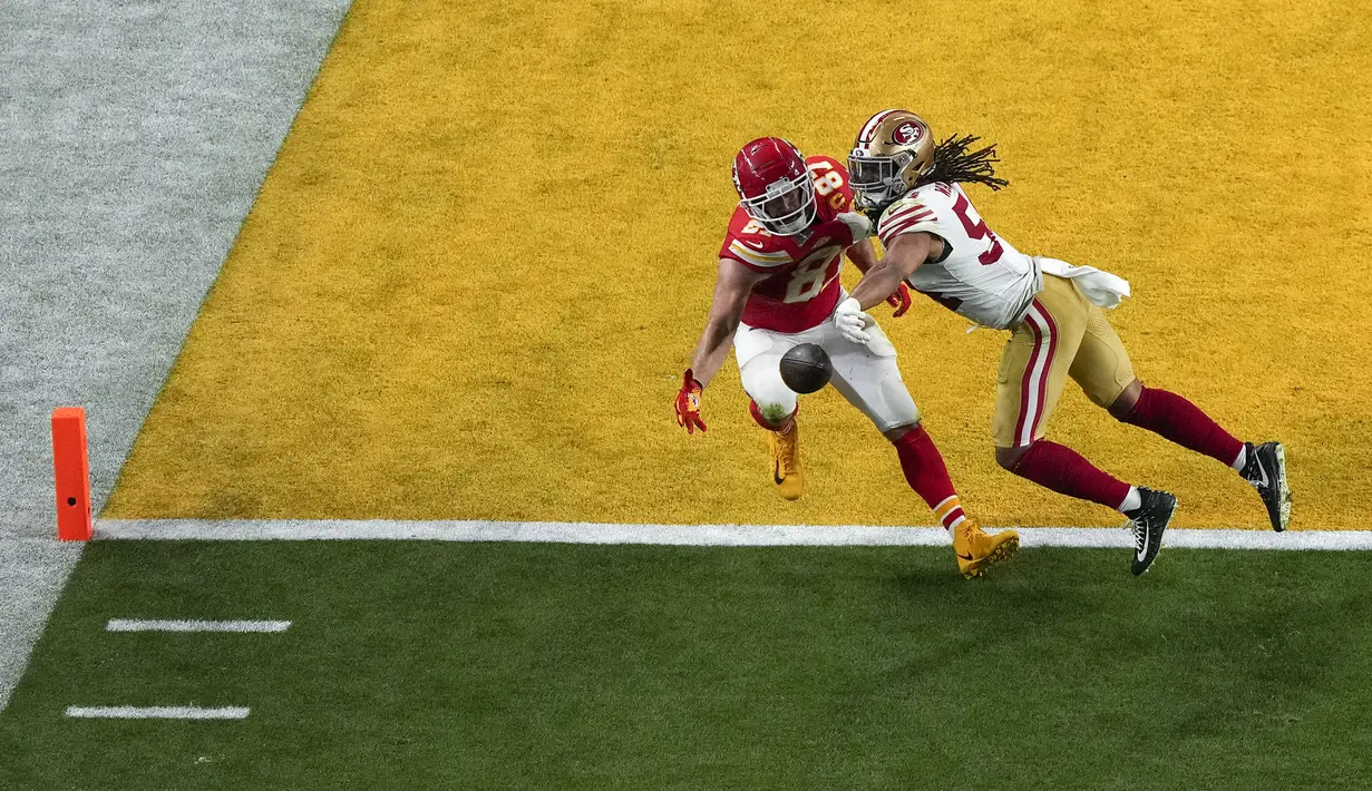 Pemain Kansas City Chiefs, Travis Kelce (kiri) berusaha menangkap bola dibayangi pemain San Francisco 49ers, Fred Warner pada laga Super Bowl  LVIII di Las Vegas, Amerika Serikat, Minggu (11/02/2024) waktu setempat. (AP Photo/David J Phillip)