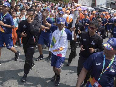 Pebalap sepeda legendaris Indonesia, Sutiyono, berlari saat mengikuti pawai obor Asian Games XVIII di Lampung, Rabu (8/8/2018). Sebanyak 53 kota di Indonesia akan dilalui oleh obor Asian Games. (Bola.com/Reza Bachtiar)