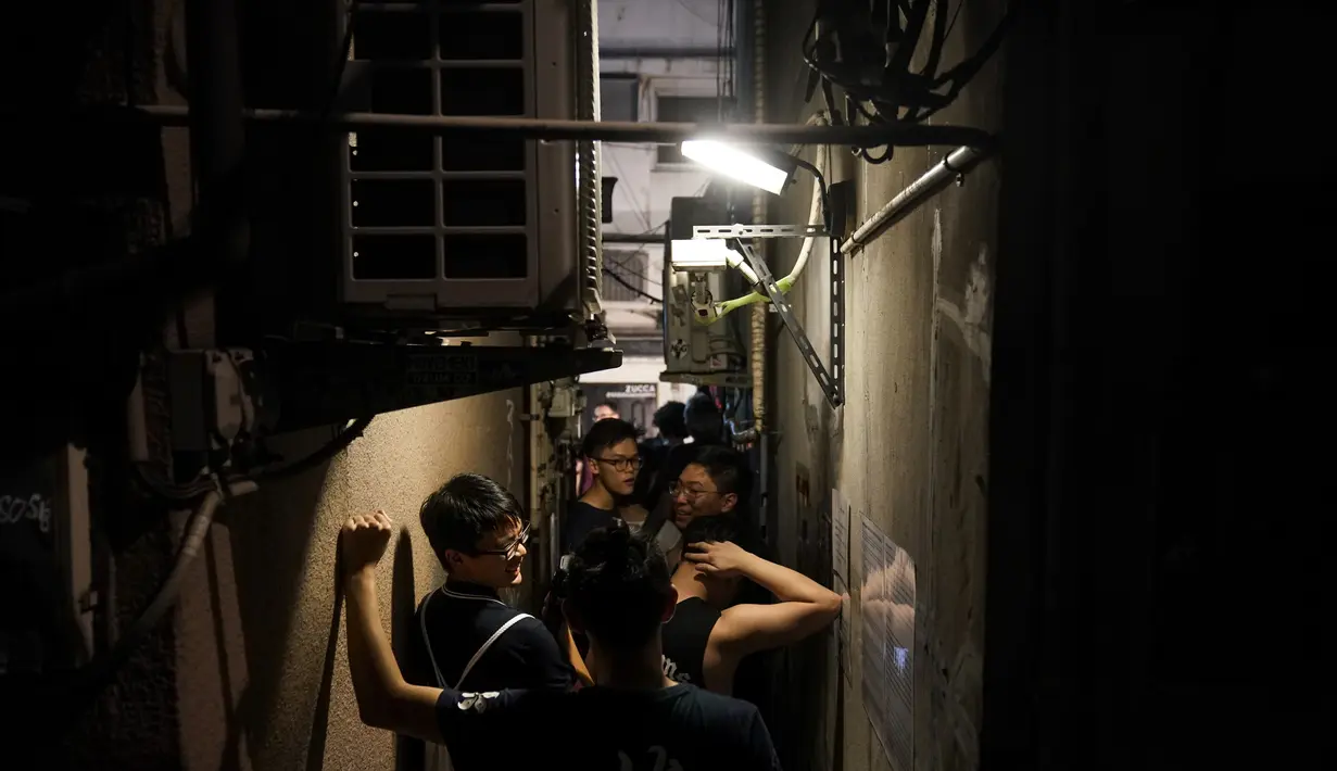 Turis berjalan di sepanjang lorong sempit di luar restoran ramen di Golden Gai di distrik Shinjuku Tokyo (26/7/2019). Di area ini, pengambilan foto dan video untuk semua keperluan di jalan dilarang tanpa izin dari asosiasi promosi bisnis di daerah tersebut. (AP Photo / Jae C. Hong)