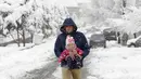 Seorang pria berjalan dengan anak kecil di tengah salju di Ibu Kota Teheran, Iran, Minggu (28/1). Sekitar 20 provinsi di barat dan utara Iran terkena dampak hujan salju. (AFP PHOTO/ATTA KENALI)