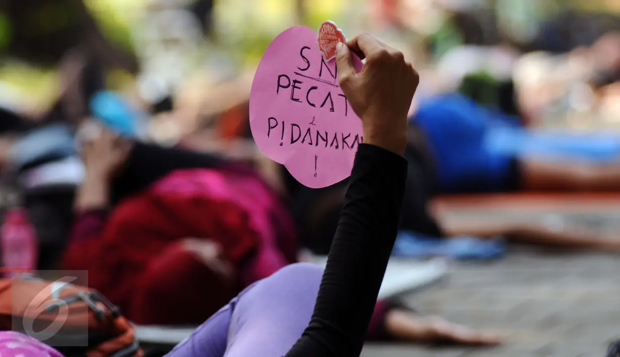 Salah satu perempuan pegiat antikorupsi menunjukkan tulisan saat melakukan yoga dan aksi penyampaian pendapat di Taman Suropati, Jakarta, Minggu (6/12). Kegiatan ini juga bentuk peringatan Hari Anti korupsi. (Liputan6.com/Helmi Fithriansyah)