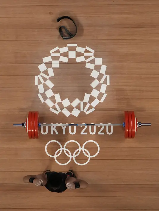 Lifter Indonesia Rahmat Erwin Abdullah menyapa penonton saat berlaga dalam cabang olahraga angkat besi 73 kg putra pada Olimpiade Tokyo 2020 di Tokyo, Jepang, Rabu (28/7/2021). Sebelumnya, Rahmat Erwin hanya membidik posisi delapan besar di kelas 73 kg Olimpiade Tokyo 2020. (AP Photo/Luca Bruno)