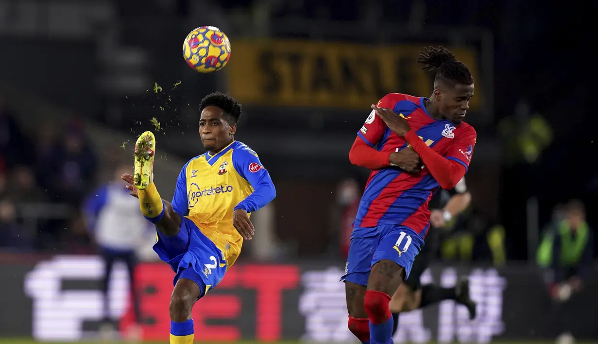 Bek Southampton Kyle Walker-Peters berebut bola dengan penyerang Crystal Palace Wilfried Zaha pada pertandingan pekan ke-17 Liga Inggris di Selhurst Park, Kamis (16/12/2021) dini hari WIB). Laga tanding antara Crystal Palace vs Southampton berbagi poin dengan skor akhir 2-2.  (Adam Davy/PA via AP)