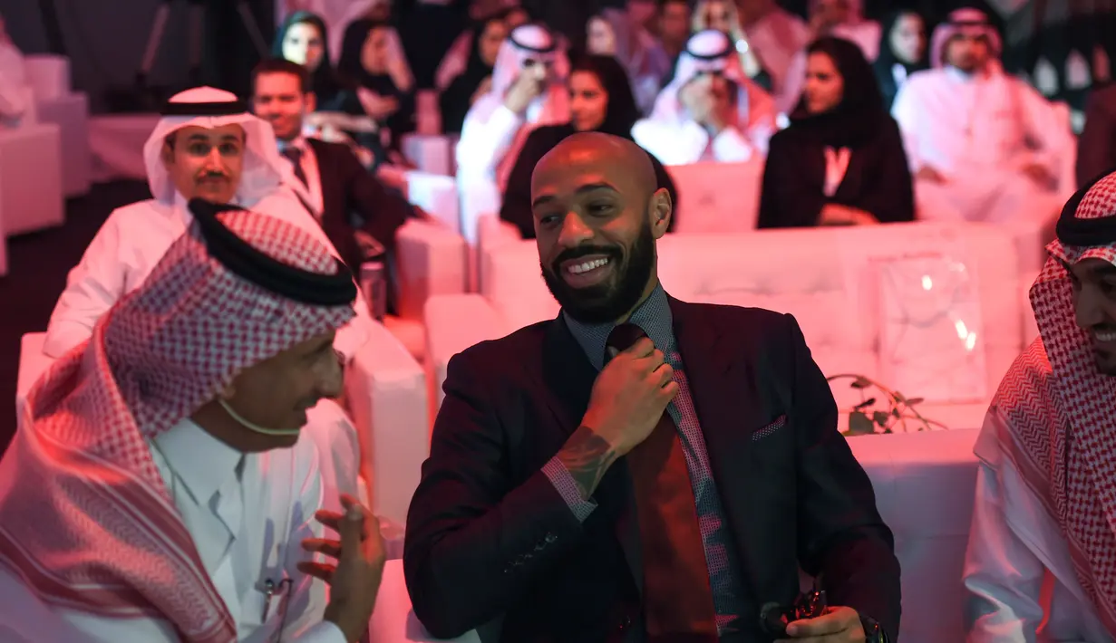 Mantan pemain Arsenal, Thierry Henry (tengah) merapihkan dasi saat menghadiri konferensi Quality of Life Program 2020 di ibukota Saudi Riyadh (3/5). Program ini adalah salah satu program realisasi visi Arab Saudi 2030. (AFP Photo/Fayez Nureldine)