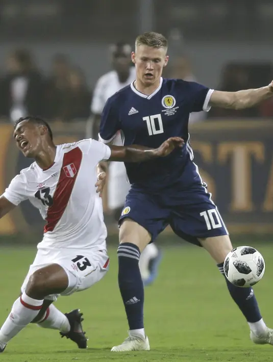 Pemain Peru, Renato Tapia (kiri) jatuh saat berebut bola dengan pemain Skotlandia, Scott Mc Tominay pada laga uji coba di Lima, Peru, (29/5/2018). Peru menang 2-0. (AP/Martin Mejia)