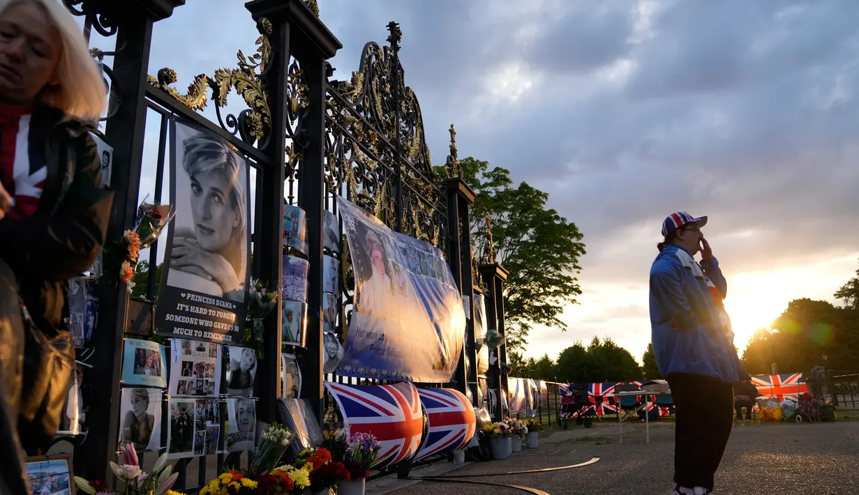 <p>Matahari mulai terbit saat dua orang berkumpul di depan potret dan pesan kenang-kenangan Putri Diana yang dipajang di gerbang Istana Kensington, London, Rabu (31/8/2022). Hari ini menandai peringatan 25 tahun wafatnya Putri Diana dalam sebuah kecelakaan mobil Paris. (AP Photo/Alastair Grant)</p>