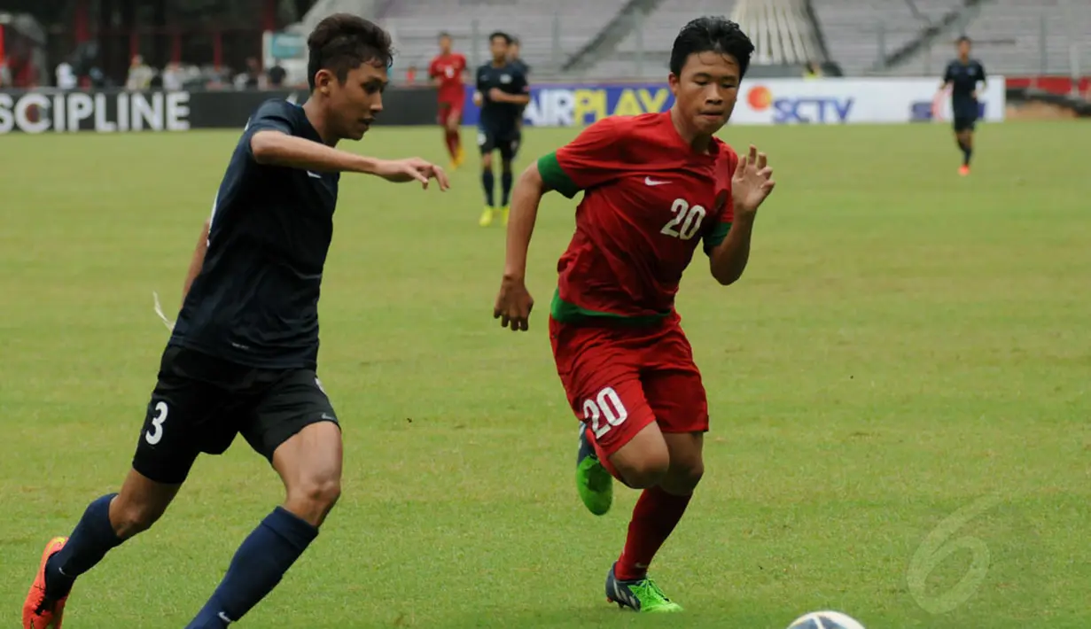 Pemain belakang timnas U-19 Singapura, Hairyl Muhaimin bin Abdul Rahim (kiri) berusaha menghalangi pergerakan penyerang timnas U-19 Indonesia, Justin Stephen saat berlaga di Stadion GBK Jakarta, (8/12/2014). (Liputan6.com/Helmi Fithriansyah)