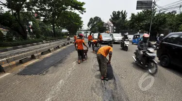 Sejumlah petugas mengaspal jalanan yang berlubang di Jalan Kramat Raya, Jakarta, Rabu (25/2/2015). Perbaikan jalan rusak pascabanjir terus dikebut Dinas Pekerjaan Umum (DPU) DKI Jakarta. (Liputan6.com/Faizal Fanani)