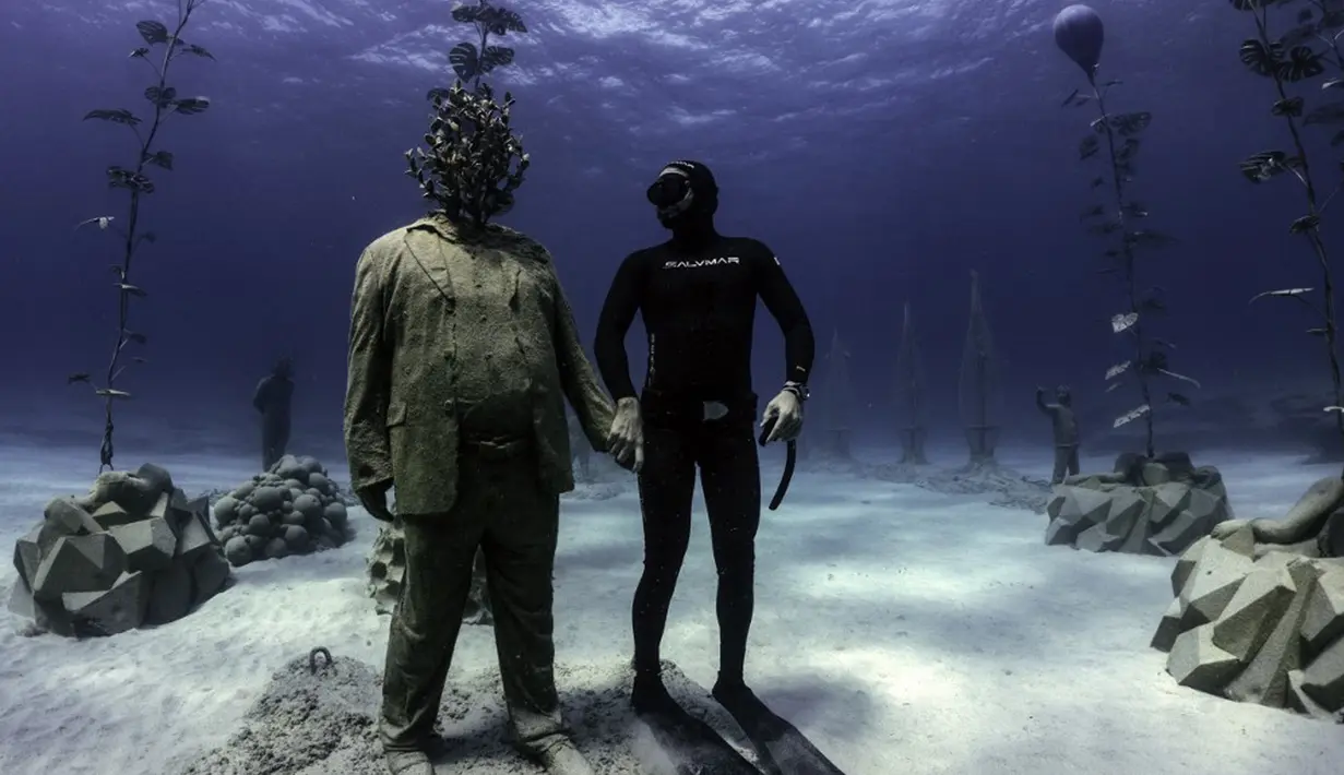 Penyelam bebas Angels Savvas berpose dengan patung di taman patung bawah laut MUSAM, Ayia Napa, Siprus, 18 September 2021. MUSAM disebut sebagai hutan bawah laut pertama di dunia. (EMILY IRVING-SWIFT/AFP)