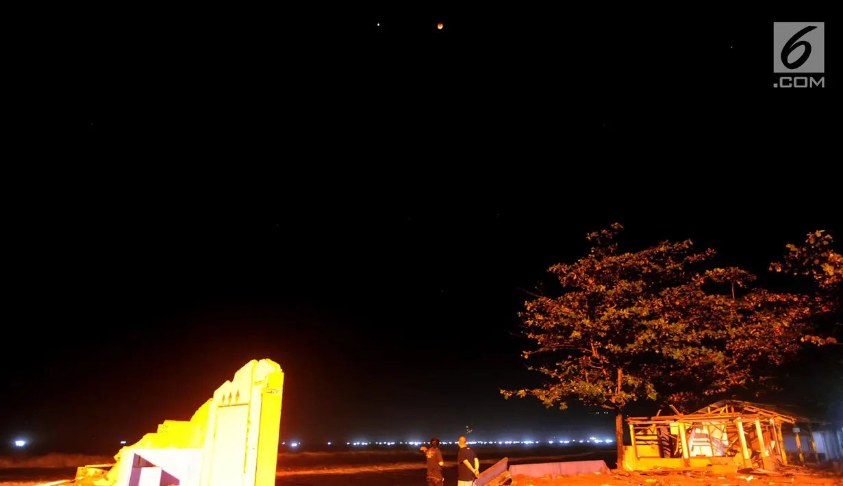 Warga menyaksikan pemandangan planet Mars berdampingan dengan gerhana bulan total terlihat di Karang Hawu, Pelabuhan Ratu, Sukabumi, Sabtu (28/7) dini hari. Fenomena alam ini menjadi gerhana Bulan paling lama Abad 21.  (Merdeka.com/Arie Basuki)