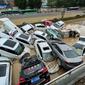 Mobil-mobil terendam banjir setelah hujan lebat melanda kota Zhengzhou di provinsi Henan tengah China (21/7/2021). Luapan sungai menggenangi jalan-jalan dan membuat kendaraan terbawa arus setelah curah hujan 200 mm turun dalam satu jam. (AFP/STR)
