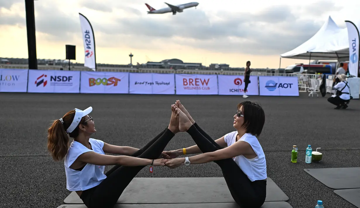 Sekitar 500 peserta yoga dan influencer yang siap dengan kamera mulai berdatangan pada pukul 5:00 pagi, berjalan dalam kegelapan menuju matras mereka di landasan pacu. (MANAN VATSYAYANA / AFP)