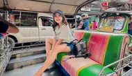 Kiky Saputri mengenakan busana kasual saat naik tuk tuk. Dia mengenakan kaos yang dipadukan dengan celana hot pants. "Naik kereta api, tuk tuk tuk.. Seru banget woy naik tuk-tuk wkwkwkw Sampe mau kejungkal-jungkal," tulisnya. (Foto: Instagram/ kikysaputrii)