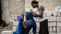 Seorang wanita saat dikepang rambutnya di pemukiman informal Elechi Phase 3 di Port Harcourt, Nigeria selatan (14/2). Nigeria akan mengadakan pemilihan presiden dan parlemen pada tanggal 16 Februari 2019. (AFP Photo/Yasuyoshi Chiba)