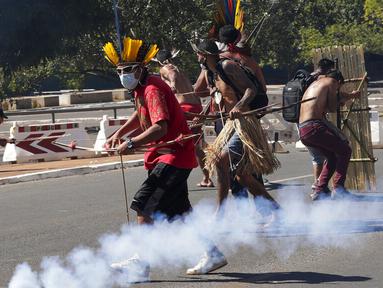 Penduduk asli Brasil bentrok dengan polisi saat demo menentang RUU Reformasi Agraria di luar Kongres di Brasilia, Brasil, Selasa (22/6/2021). Penduduk asli Brasil menilai RUU Reformasi Agraria akan membatasi pengakuan lahan reservasi. (AP Photo/Eraldo Peres)
