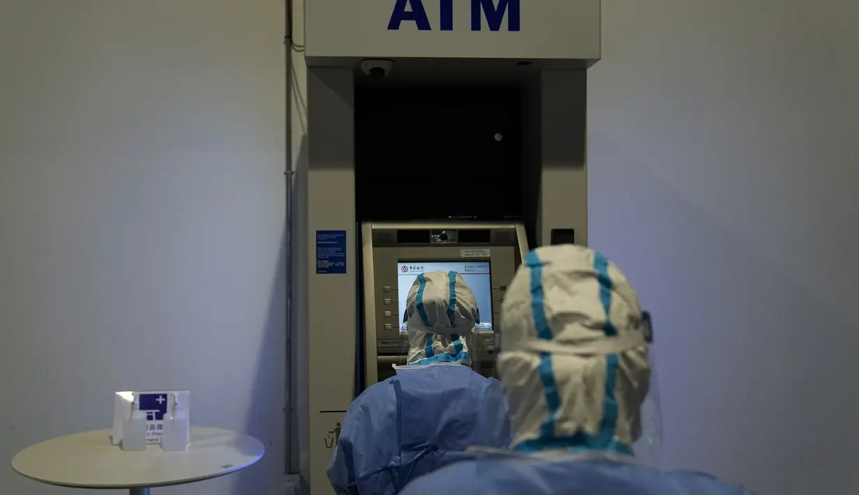 Dua pekerja medis mengambil sampel dari ATM untuk pengujian COVID-19 di pusat media utama di Olimpiade Musim Dingin 2022 di Beijing, 11 Februari 2022. Tak hanya manusia, penyelenggara Olimpiade Beijing juga melakukan tes pada gagang pintu, tombol lift, sofa dan mesin ATM. (AP Photo/Jae C.Hong)