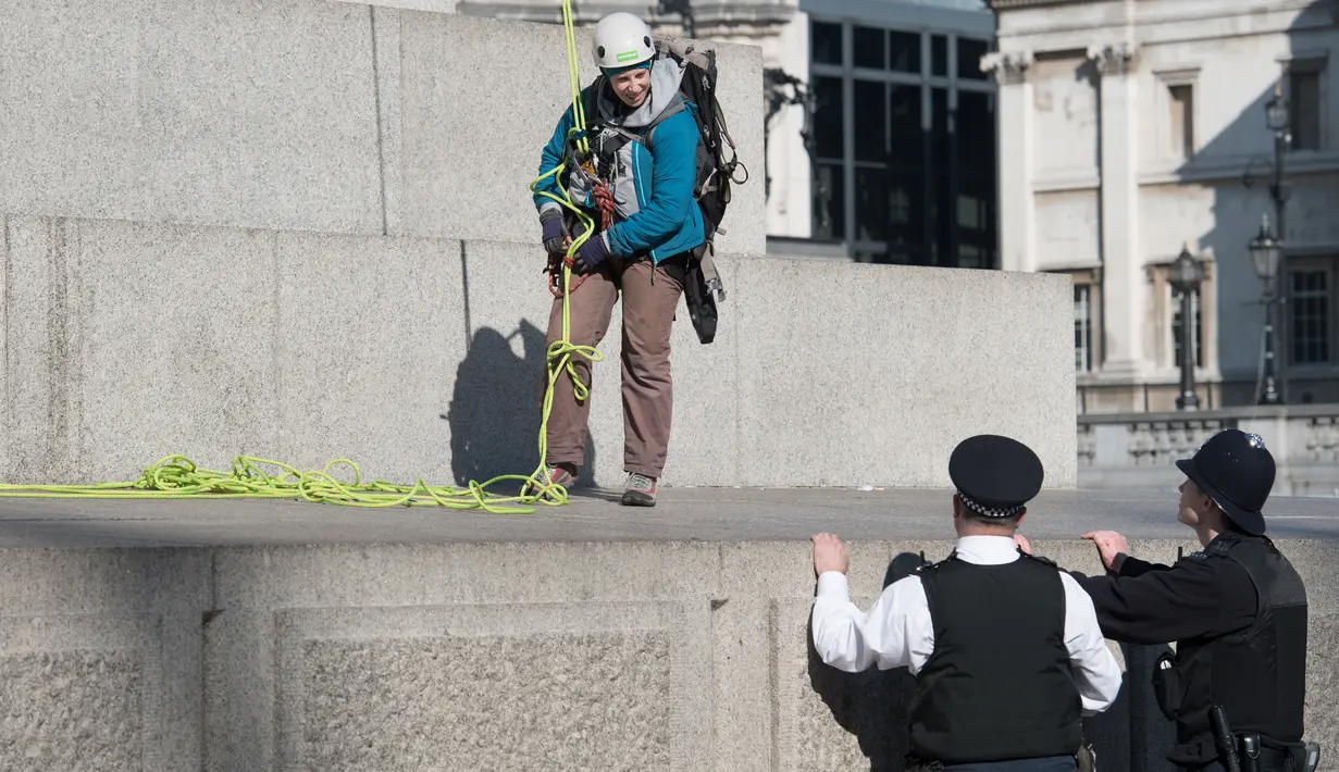 Polisi saat akan menangkap dua aktivis Greenpeace yang memasangkan masker pada sejumlah patung bersejarah di pusat kota London, Inggris, Senin (18/4). Aksi unik itu dilakukan untuk memprotes kualitas polusi udara di kawasan tersebut. (Leon NEAL/AFP)