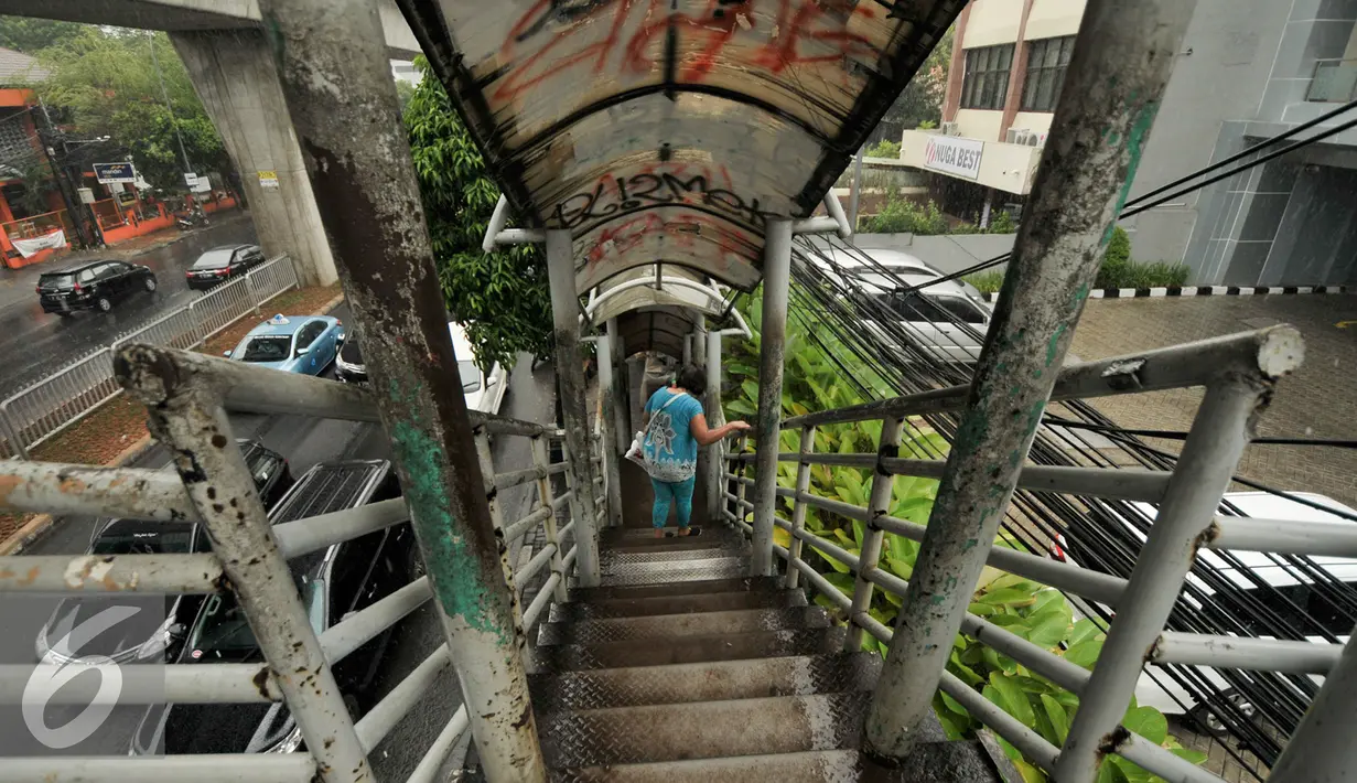 Warga menuruni tangga jembatan penyeberangan orang (JPO) di Mampang, Jakarta, Selasa (17/1). Namun karena sangat dibutuhkan, warga membuka kembali JPO ini. (Liputan6.com/Yoppy Renato)