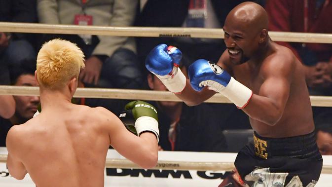 Petinju, Floyd Mayweather, berusaha memukul kickboxer, Tenshin Nasukawa, pada laga eksebisi di Saitama Super Arena, Saitama, Senin (31/1). Tanding dengan aturan tinju, Mayweather menang TKO di ronde pertama. (AFP/Toshifumi Kitamura)
