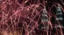 Kembang api menghiasi langit di dekat Menara Kembar Petronas Malaysia saat malam pergantian tahun di Kuala Lumpur, Malaysia. (01/1/2018). Menara Kembar Petronas menjadi salah satu spot para wisatawan menikmati malam tahun baru. (AFP Photo / Mohd Rasfan)