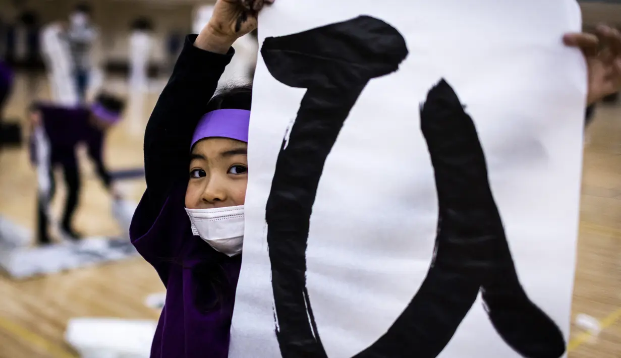 Seorang peserta menampilkan tulisan Jepang mereka selama kontes kaligrafi Tahun Baru tahunan di Tokyo (5/1/2022). Lebih dari 3.000 kaligrafer, yang telah memenuhi syarat dalam kompetisi tingkat nasional di seluruh Jepang, ikut serta dalam kontes tahunan untuk merayakan tahun baru. (AFP/Behrouz Mehri