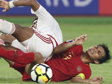Pemain Timnas Indonesia U-19, Rachmat Irianto terjatuh saat berebut bola dengan pemain Uni Emirat Arab U-19 pada penyisihan Grup A Piala AFC U-19 2018 di Stadion GBK, Jakarta, Rabu (24/10). Indonesia unggul 1-0. (Liputan6.com/Helmi Fithriansyah)