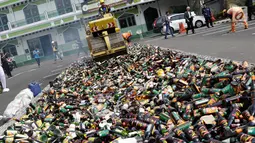 Petugas menggiling ribuan botol minuman keras (miras) menggunakan alat berat saat pemusnahan di halaman Mapolres Jakarta Selatan, Selasa (23/5). Ribuan botol ini disita dalam operasi yang dilakukan sejak Januari 2017. (Liputan6.com/Immanuel Antonius)