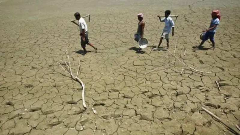 Para pekerja berjalan di atas danau yang telah kering di India (Foto: Reuters).