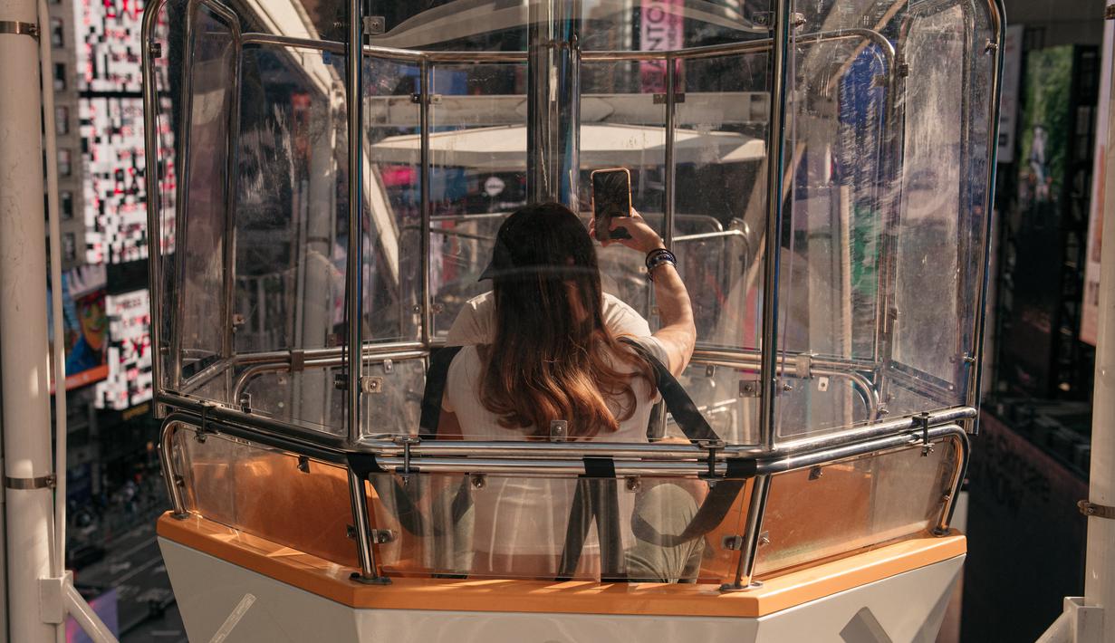 Pengunjung menikmati biangalala setinggi 110 kaki di Times Square, Manhattan, New York City, Rabu (25/8/2021). Tiket masuk umum tersedia seharga US$ 20 (Rp 287 ribu) per orang tapi dngan membayar US$ 35 (Rp 503 ribu), pengunjung dapat menghindari antrian. (Scott Heins/Getty Images/AFP)