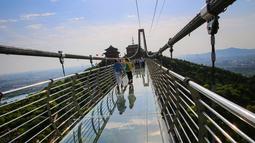 Foto yang diambil pada 4 Mei 2019 menunjukkan orang-orang berjalan di atas jembatan berlantai kaca di Huaxi Adventure Park, Provinsi Jiangsu timur China. Jembatan kaca setinggi 518 meter ini menjadi tujuan wisata favorit di China. (Photo by STR / AFP)