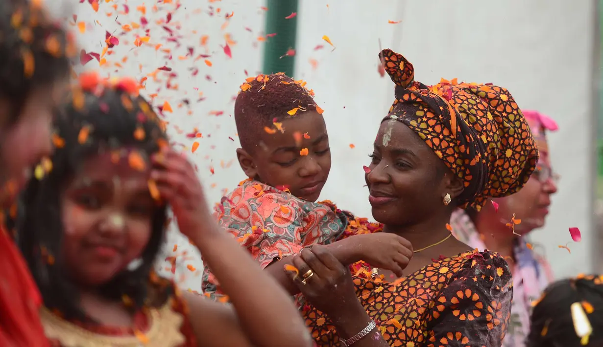 Seorang wanita Nigeria dengan anaknya Stefan bermain dengan bunga dan bubuk berwarna di sebuah acara festival Hindu Holi untuk anak-anak dengan cerebral palsy yang diselenggarakan oleh Yayasan Trishla di Allahabad (25/2). (AFP Photo/Sanjay Kanojia)