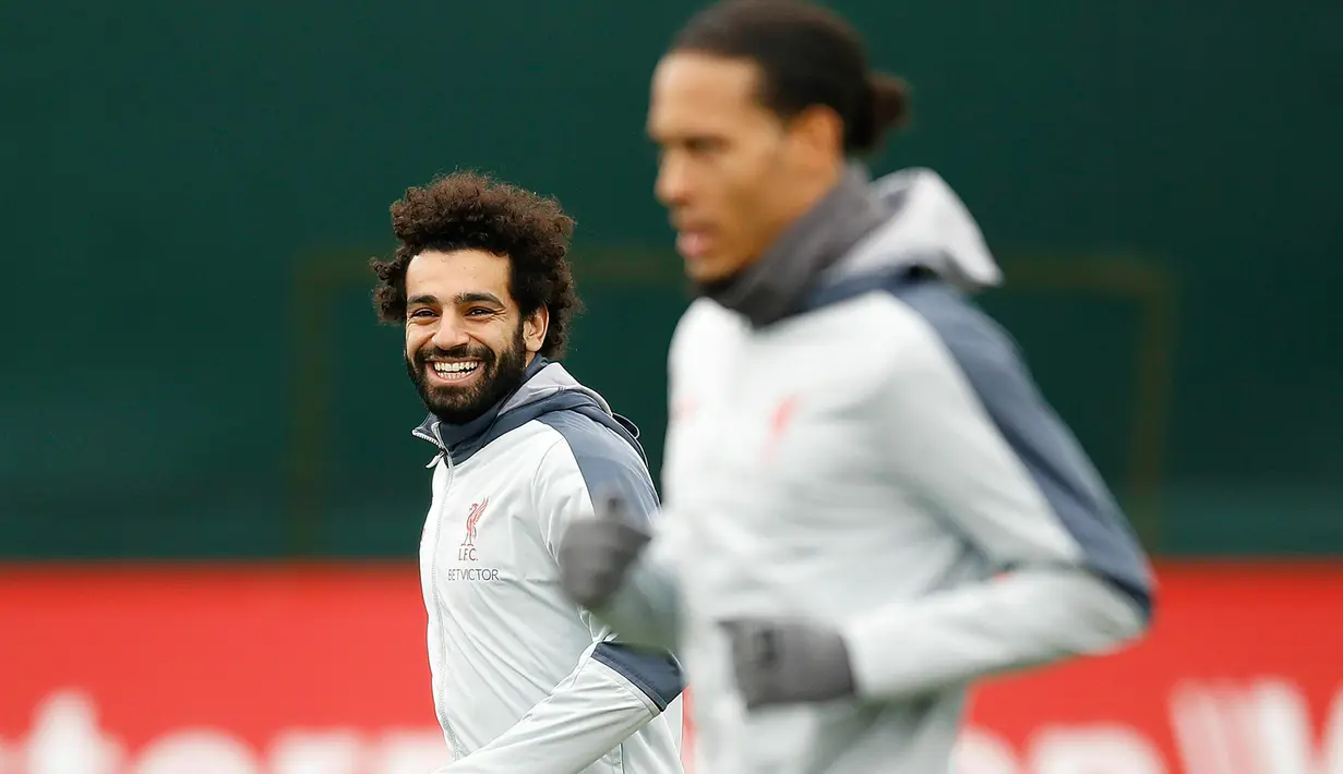 Gelandang Liverpool Mohamed Salah (kiri) tersenyum saat sesi latihan jelang menghadapi Bayern Munchen dalam leg kedua babak 16 besar Liga Champions di Melwood, Liverpool, Inggris, Selasa (12/3). (Martin Rickett/PA via AP)