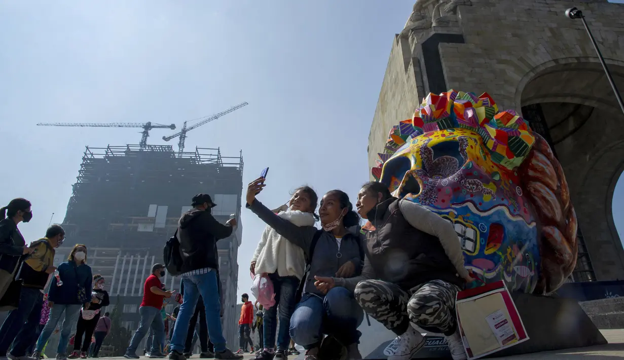 Warga berswafoto pada pameran Fridacraneos, tengkorak raksasa yang dilukis untuk menghormati mendiang seniman Meksiko Frida Kahlo, sebagai bagian dari perayaan Hari Kematian di Monumen Revolusi, Mexico City, Meksiko, 29 Oktober 2021. (Claudio CRUZ/AFP)
