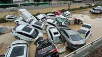 Mobil-mobil terendam banjir setelah hujan lebat melanda kota Zhengzhou di provinsi Henan tengah China (21/7/2021). Luapan sungai menggenangi jalan-jalan dan membuat kendaraan terbawa arus setelah curah hujan 200 mm turun dalam satu jam. (AFP/STR)