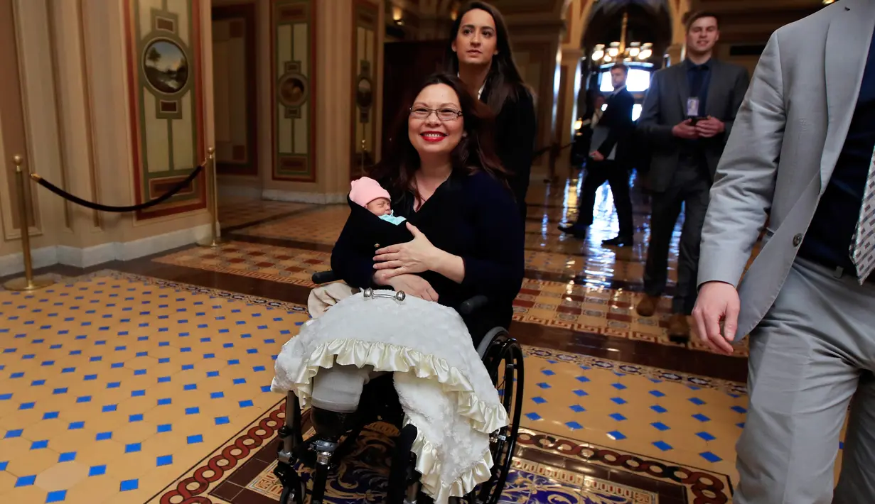 Senator negara bagian Illinois, Tammy Duckworth membawa bayinya meninggalkan ruang kongres Gedung Capitol Hill, Washington DC, Kamis (19/4). Undang-undang AS melarang anggota kongres membawa urusan pribadi ke dalam area pekerjaan. (AP/Manuel Balce Ceneta)
