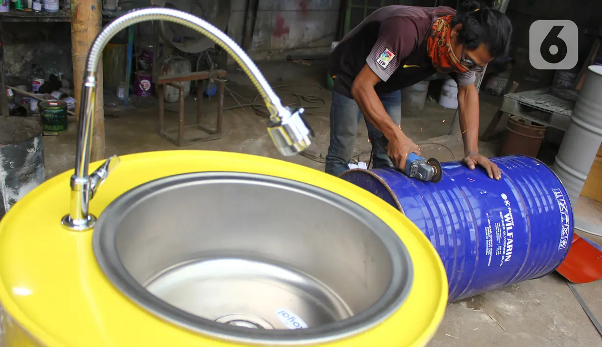 Perajin memproduksi wastafel portabel berbahan baku drum di workshop Galuh Creatives, Tangerang Selatan, Sabtu (30/5/2020). Wacana pemerintah menerapkan tatanan normal baru berimbas pada meningkatnya pesanan wastafel portabel yang dijual seharga Rp1,2 juta per unit. (merdeka.com/Arie Basuki)