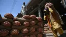 Seorang buruh Pakistan membawa sekarung bawang di sebuah pasar grosir sayuran di Islamabad (9/4). Islamabad dibangun pada 1960-an untuk menggantikan Karachi sebagai ibu kota Pakistan. (AFP Photo/Aamir Qureshi)